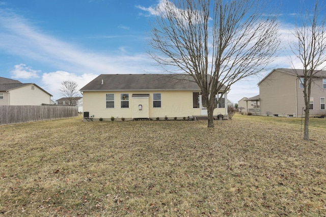 rear view of house featuring fence and a yard