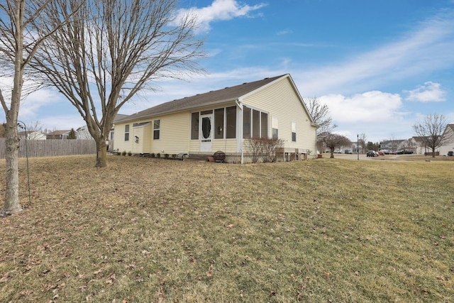 view of home's exterior with a lawn, fence, and a sunroom