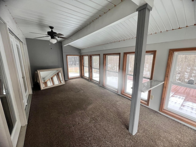 unfurnished living room featuring vaulted ceiling with beams, plenty of natural light, and carpet flooring