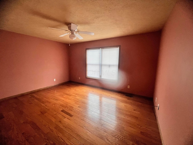 unfurnished room with light wood-type flooring, ceiling fan, a textured ceiling, and baseboards