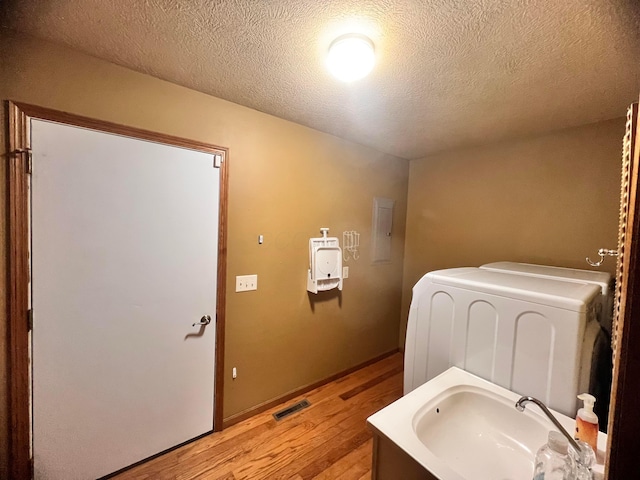 bathroom featuring washer / dryer, visible vents, wood finished floors, a textured ceiling, and a sink