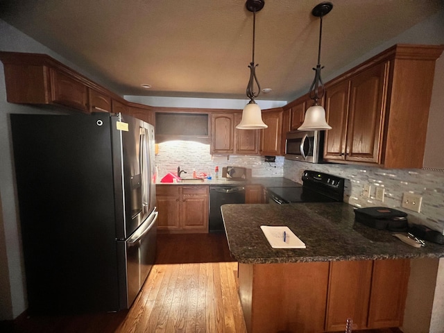 kitchen featuring stainless steel appliances, a peninsula, wood finished floors, backsplash, and decorative light fixtures