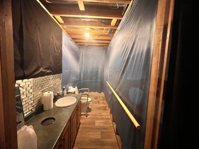 bathroom with toilet, vanity, decorative backsplash, and wood finished floors