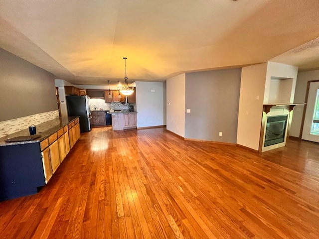 1396 Spring Village Dr, Mansfield, OH 44906 - kitchen with freestanding refrigerator, wood finished floors, backsplash, open floor plan, and a tiled fireplace