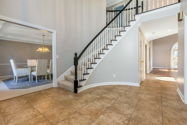 stairs featuring tile patterned flooring, a notable chandelier, a high ceiling, and baseboards