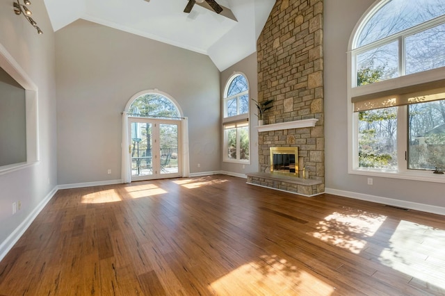 unfurnished living room with visible vents, ceiling fan, a fireplace, wood finished floors, and high vaulted ceiling