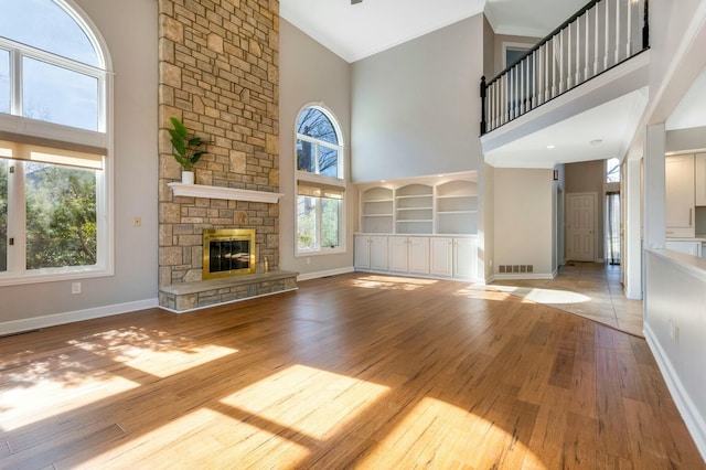 unfurnished living room featuring crown molding, a fireplace, visible vents, and a towering ceiling