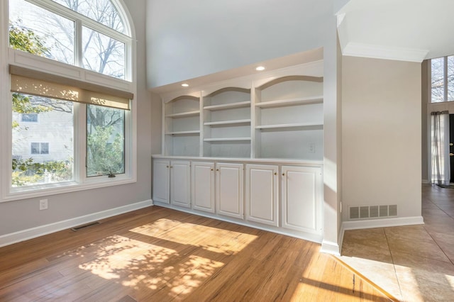 unfurnished room featuring visible vents, a healthy amount of sunlight, and baseboards