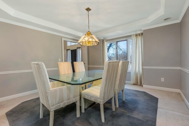 carpeted dining room featuring crown molding, baseboards, and a raised ceiling