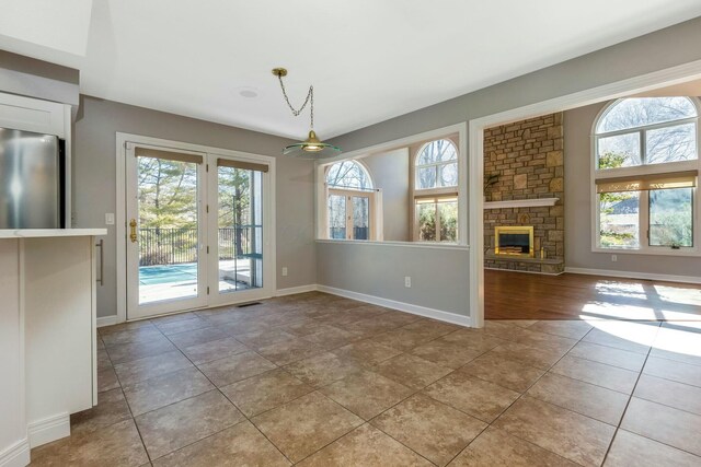 unfurnished dining area with visible vents, plenty of natural light, light tile patterned flooring, and a fireplace