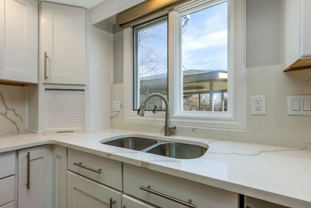 kitchen featuring white cabinetry, a healthy amount of sunlight, backsplash, and a sink