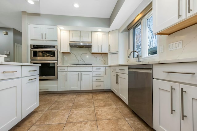 kitchen with under cabinet range hood, light countertops, light tile patterned floors, appliances with stainless steel finishes, and white cabinetry