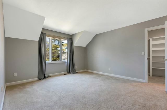 additional living space with baseboards, lofted ceiling, and carpet flooring