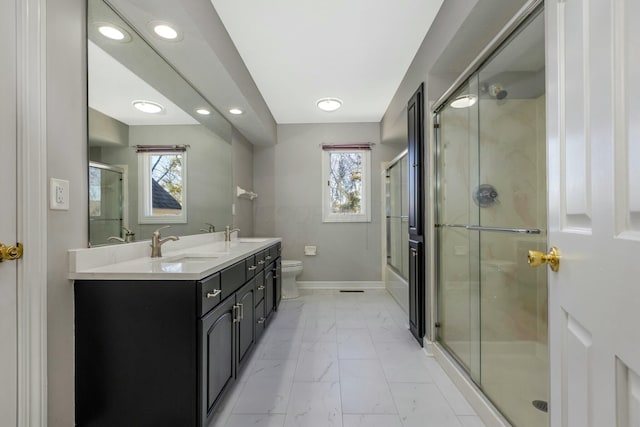 bathroom with marble finish floor, a shower stall, a healthy amount of sunlight, and a sink