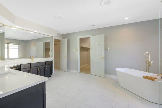 full bath with a spacious closet, marble finish floor, baseboards, and a freestanding tub