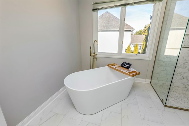 bathroom with a freestanding tub, baseboards, marble finish floor, and a walk in shower