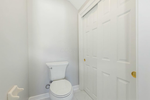 bathroom with toilet, baseboards, and marble finish floor