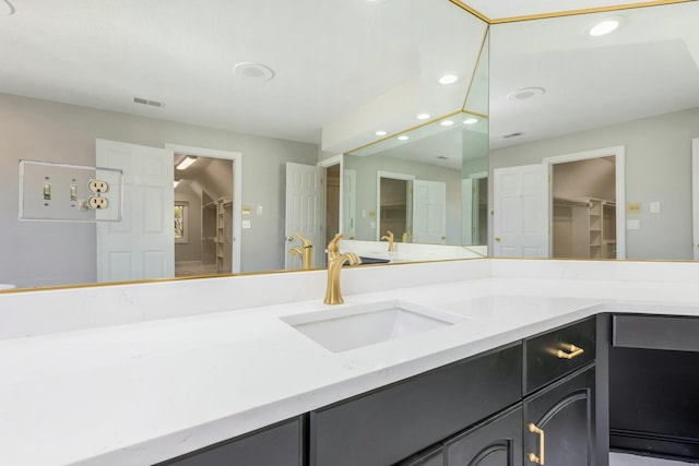 bathroom with vanity, a walk in closet, recessed lighting, and visible vents