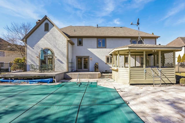 back of house with stucco siding, a patio, and a fenced in pool