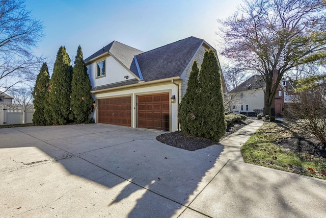 view of property exterior featuring roof with shingles, concrete driveway, an attached garage, and fence