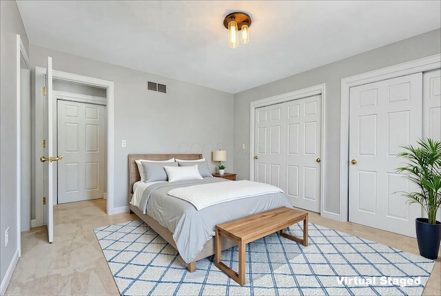 bedroom with visible vents, baseboards, and multiple closets