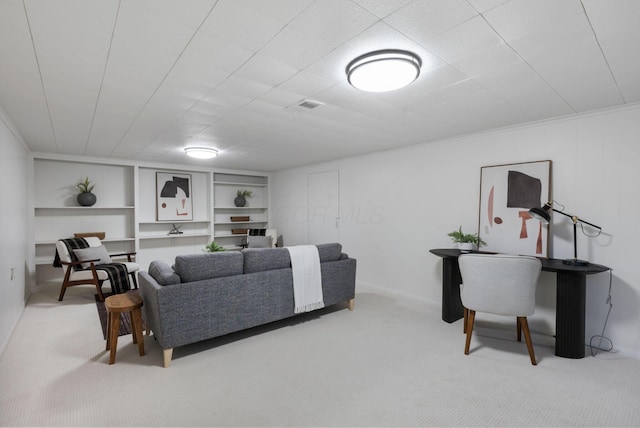 living area with built in shelves, visible vents, and light colored carpet