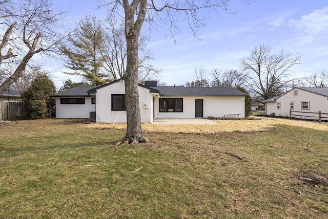 rear view of house with a yard, fence, stucco siding, and a patio