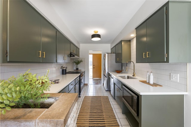 kitchen with backsplash, appliances with stainless steel finishes, light tile patterned flooring, a sink, and under cabinet range hood