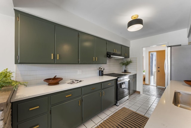 kitchen featuring light tile patterned floors, tasteful backsplash, light countertops, appliances with stainless steel finishes, and under cabinet range hood