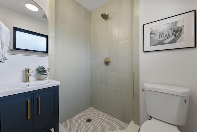 full bathroom with a tile shower, vanity, and toilet