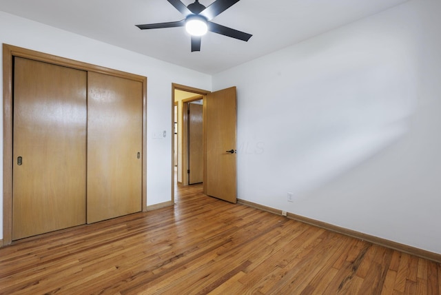 unfurnished bedroom with a closet, light wood-type flooring, a ceiling fan, and baseboards