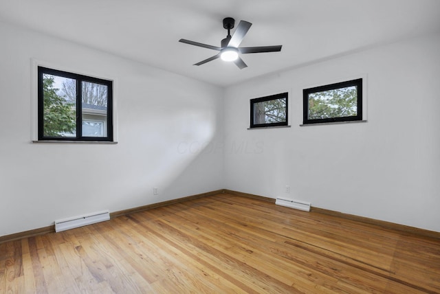 empty room featuring ceiling fan, light wood finished floors, a baseboard radiator, and baseboards