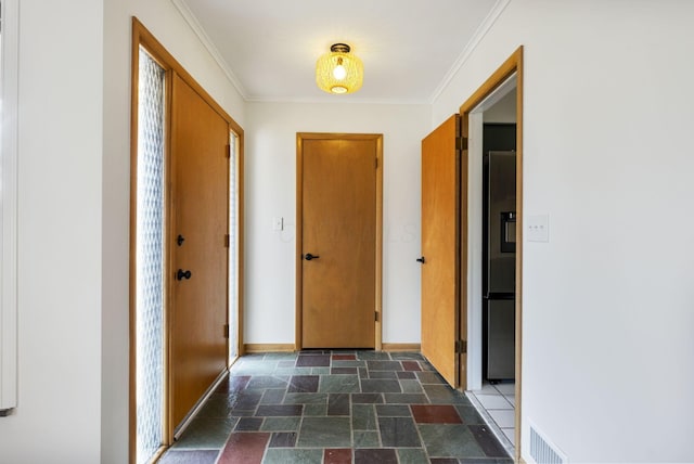 hallway featuring baseboards, visible vents, ornamental molding, and stone tile flooring