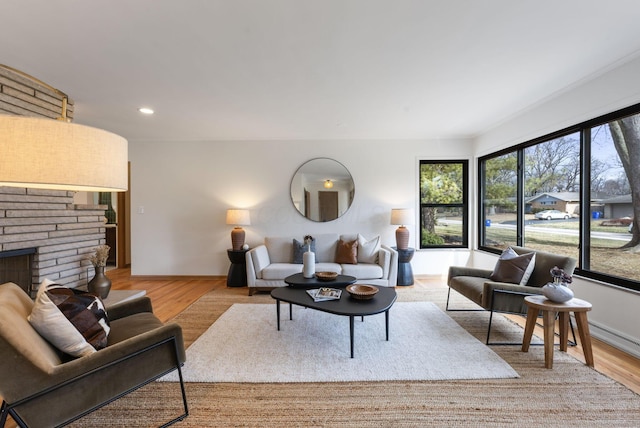 living area featuring recessed lighting, a fireplace, baseboards, and wood finished floors