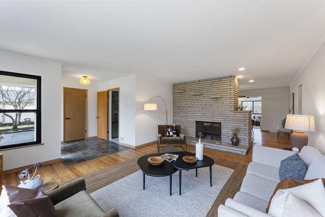 living area featuring recessed lighting, a fireplace, wood finished floors, baseboards, and crown molding