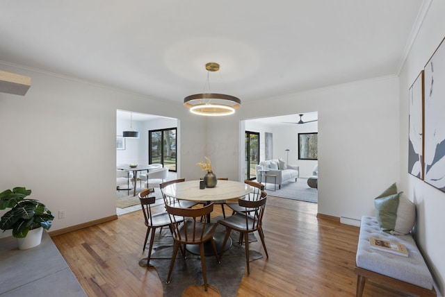 dining area with ornamental molding, light wood-type flooring, a baseboard heating unit, and baseboards