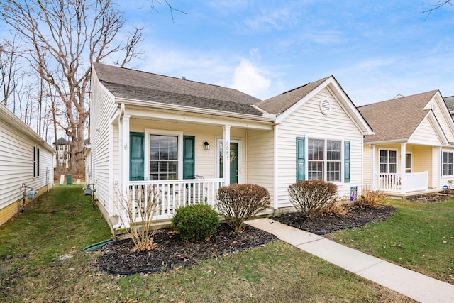 view of front of property with a porch, roof with shingles, and a front lawn