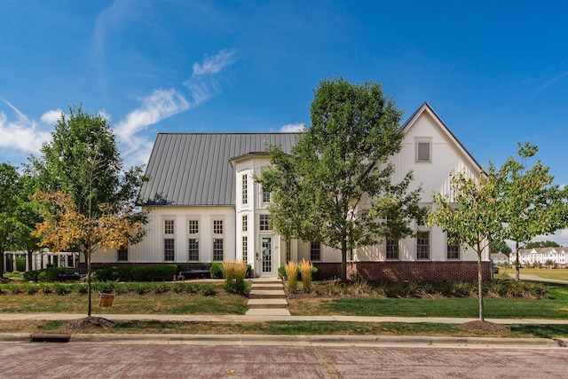 view of front facade with metal roof, brick siding, and a standing seam roof