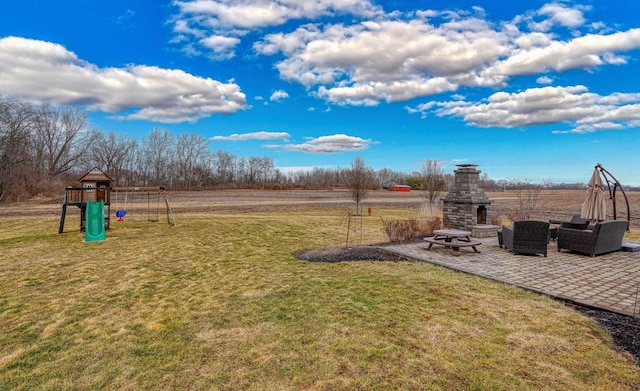 view of yard featuring an outdoor stone fireplace, a playground, and a patio