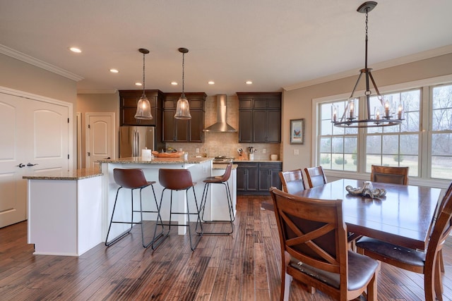 kitchen featuring a kitchen island, wall chimney range hood, backsplash, freestanding refrigerator, and dark wood finished floors