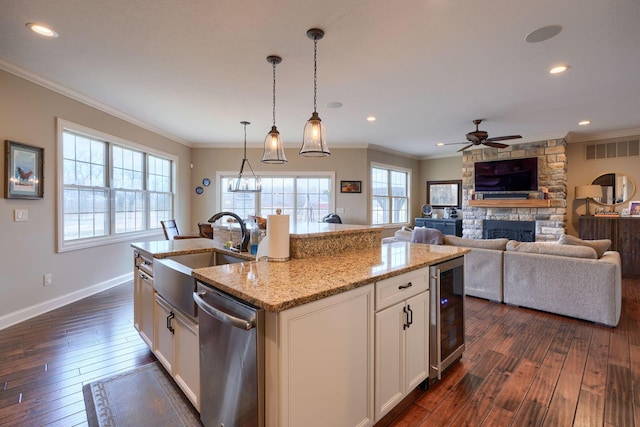 kitchen with beverage cooler, dark wood-style floors, a stone fireplace, stainless steel dishwasher, and a sink