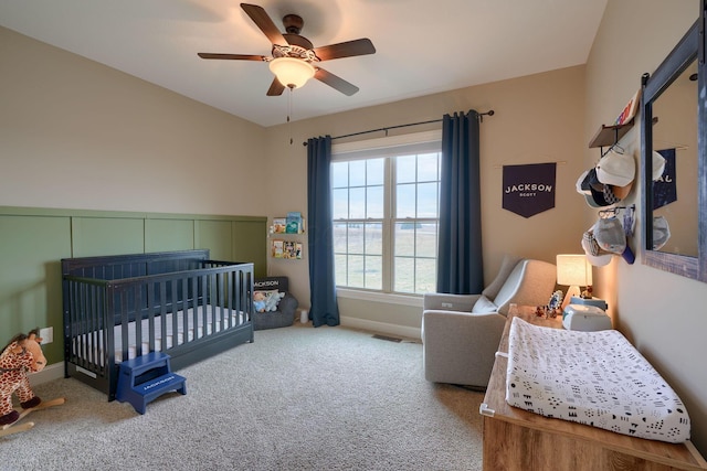 bedroom featuring a ceiling fan, carpet flooring, a crib, and baseboards