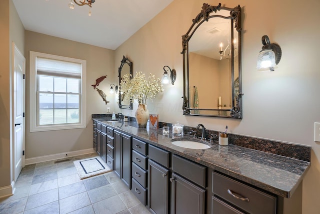 bathroom with double vanity, baseboards, a sink, and tile patterned floors