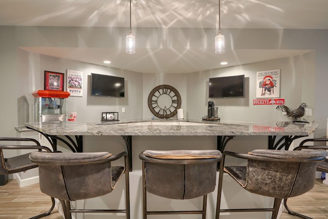 bar featuring light wood-type flooring, wet bar, baseboards, and pendant lighting