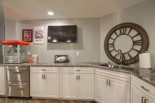 kitchen with dark stone counters, white cabinetry, a sink, and recessed lighting