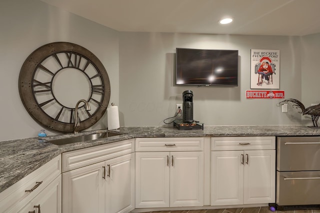 kitchen featuring recessed lighting, white cabinetry, a sink, and dark stone countertops