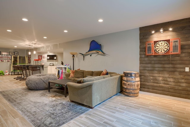 living room featuring wood tiled floor, wooden walls, and recessed lighting