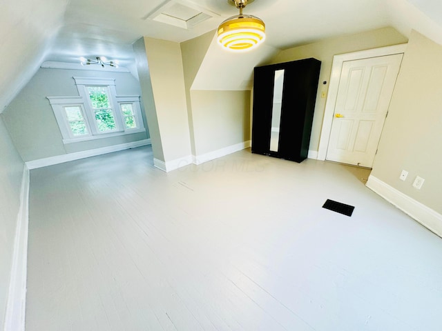 additional living space featuring light wood-style floors, lofted ceiling, and baseboards