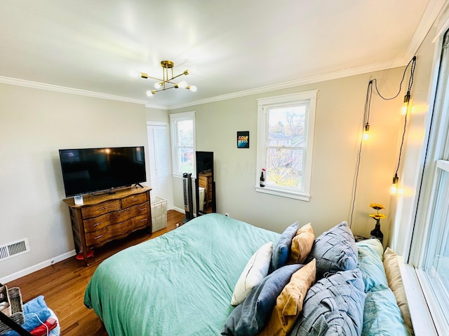 bedroom with wood finished floors, visible vents, baseboards, ornamental molding, and an inviting chandelier