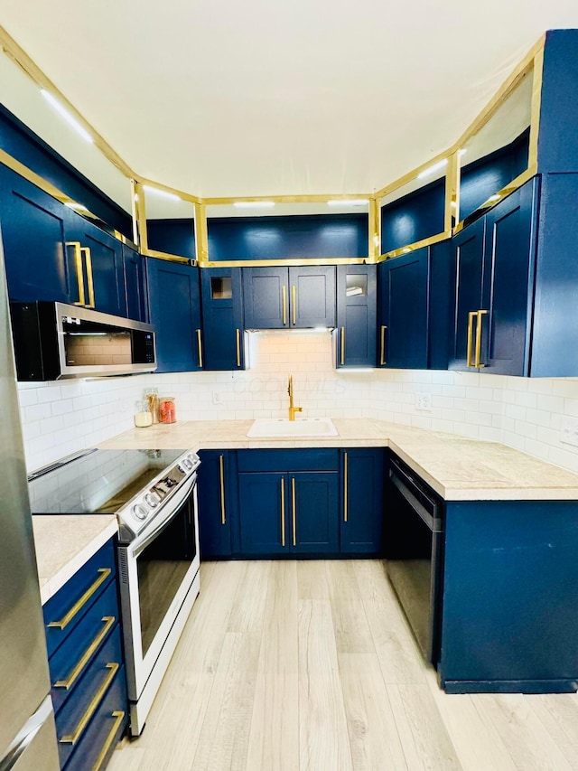 kitchen with blue cabinets, electric range, a sink, dishwasher, and stainless steel microwave